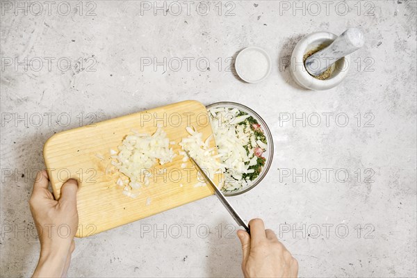 Top view of adding chopped onion into a bowl with minced meat. Making of meatballs