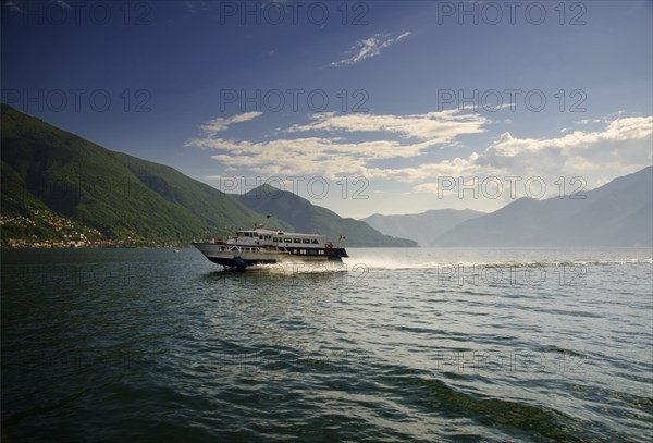 Jetfoil Passenger Ship Travel on Lake Maggiore with Mountain and Blue Sky with Clouds in a Sunny