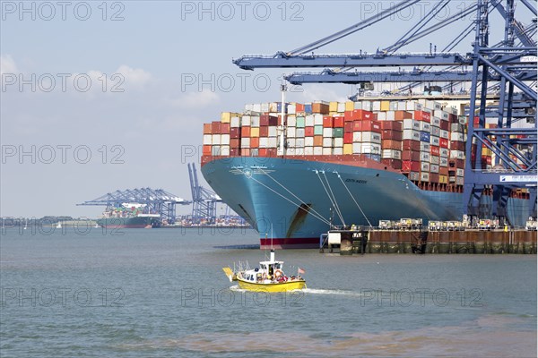 Small foot ferry passenger boat dwarfed by huge Edith Maersk container ship, Port of Felixstowe,