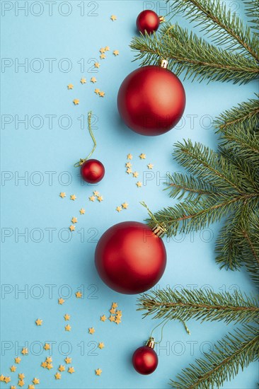 Christmas or New Year composition. Decorations, red balls, fir and spruce branches, on a blue paper