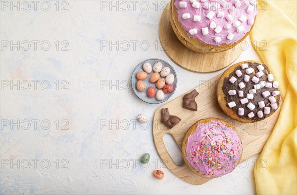 Homemade glazed and decorated easter pies with chocolate eggs and rabbits on a white concrete