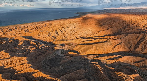 Landscape of eroded hills, badlands at sunset, Issyk Kul Lake in the background, aerial view,