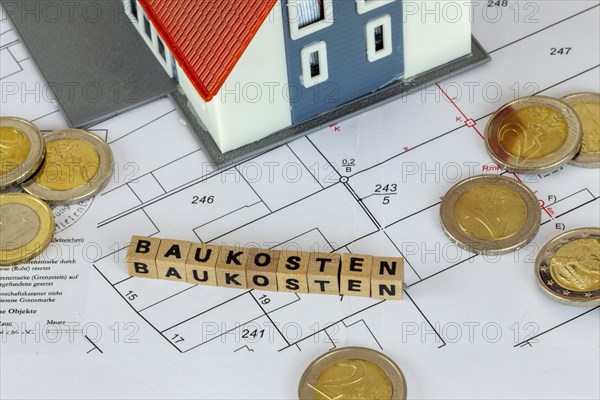 Symbolic image of construction costs: model house with bay letter cubes