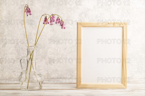 Wooden frame with pink dicentra, broken heart in glass on gray concrete background. side view, copy