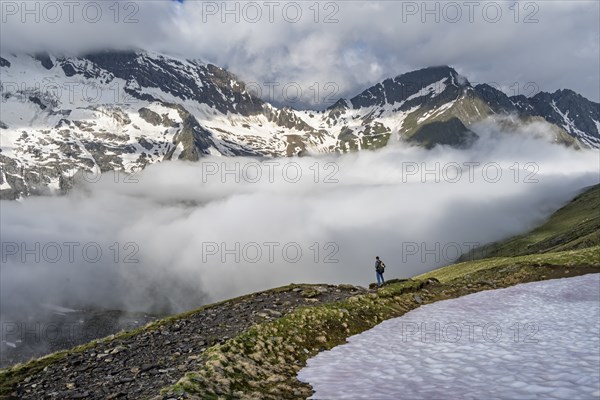 Mountaineer in front of mountain landscape with high fog in the valley, summit Hochfeiler and