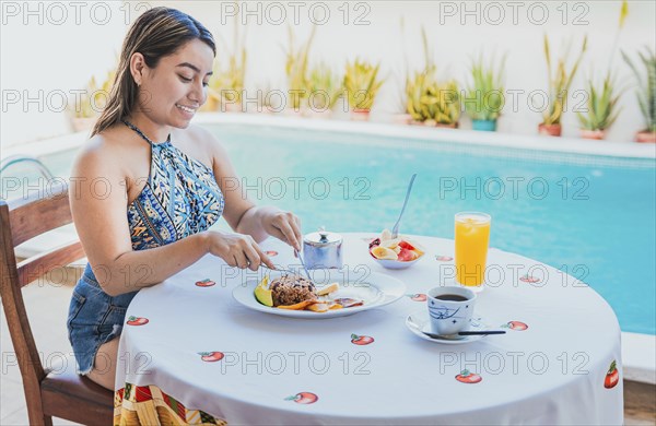 Woman on vacation having breakfast near swimming pool. Breakfast concept near swimming pool,