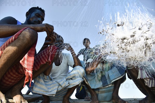 Fishermen knitting fishing net in the banks of Beki river, in Barpeta district of Assam, India on