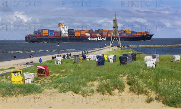 Beach promenade with landmark Kugelbake and container ship in the district of Döse, North Sea spa