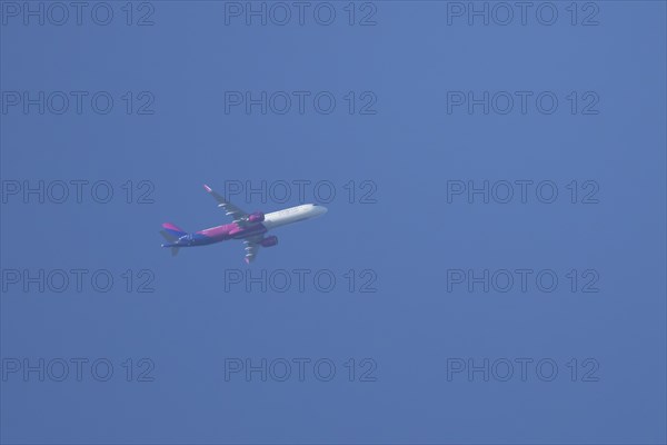 Airbus A320 aircraft of Wizz air airlines in flight across a blue sky, England, United Kingdom,