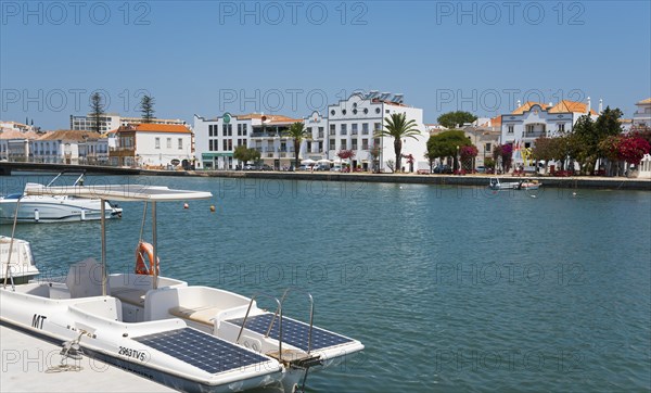 Riverside town with boats on a promenade under a clear sky in the Algarve, Gilão River, Gilao,