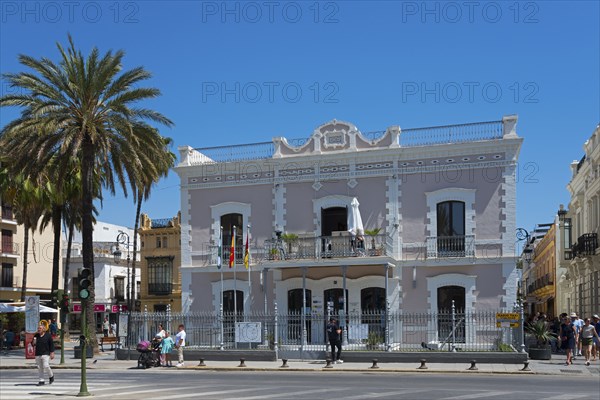 Large historical building with palm trees in front of it, people at a crossroads, Ayuntamentio,