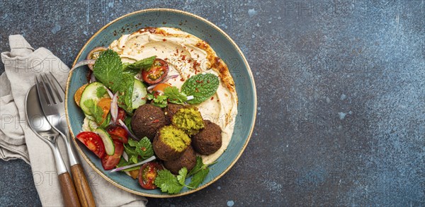 Middle Eastern Arab meal with fried falafel, hummus, vegetables salad with fresh green cilantro and