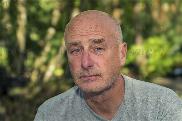 Portrait, man, camera view, sad, beard, unshaven, bald, background blurred, edge of forest,