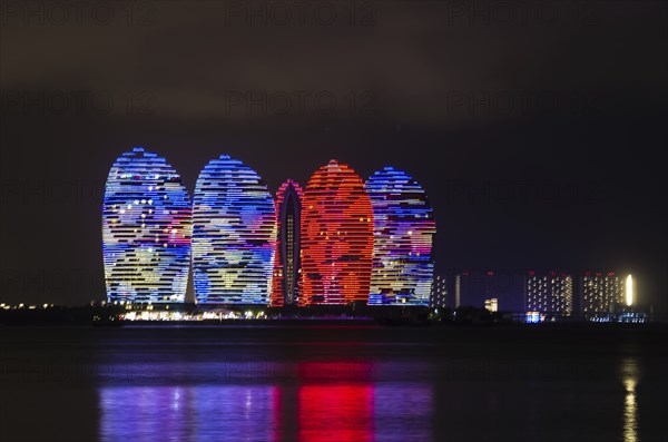 Scenic night view of buldings on Phoenix island with backlight and reflection in a sea in Sanya,