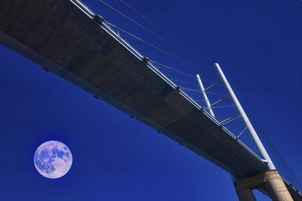 A modern bridge at night, illuminated by a clear sky with a full moon, Rügenbrücke, Stralsund,