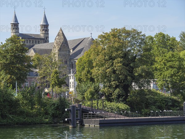 Large church near a river, surrounded by trees in a historic city, maastricht. netherlands