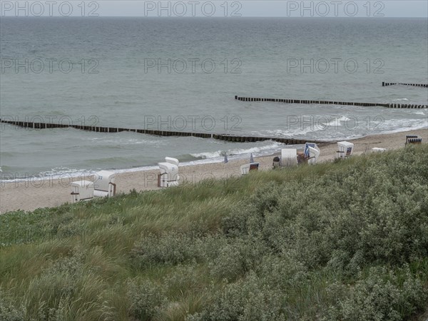 The beach features a row of beach chairs overlooking the sea, which is protected by wooden