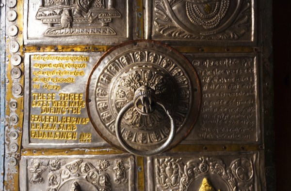 The ornamental metal door knocker and door at the entrance to Bhimakali Temple covered in