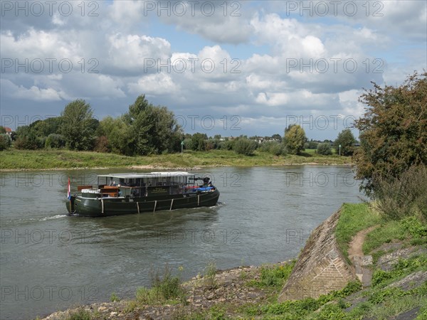 A boat sailing on a calm river on a cloudy day, zutphen, the netherlands
