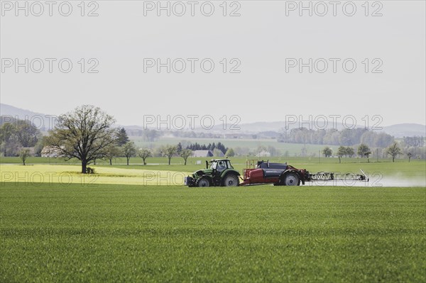 A tractor with a trailed field sprayer drives in a field in Vierkirchen, 12/04/2024
