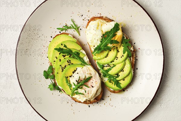 Sandwich with cream cheese, sliced avocado and boiled egg, arugula, on grainy bread, homemade,