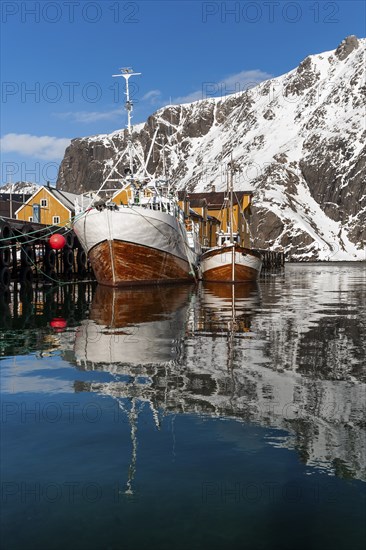 Fishing boats, fishing village with yellow houses in front of snowy mountains, Nusfjord,