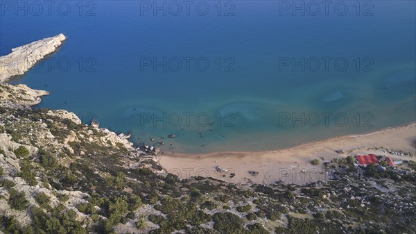 Aerial view of a secluded beach with clear water and small huts on the shore, Tsambika Beach,