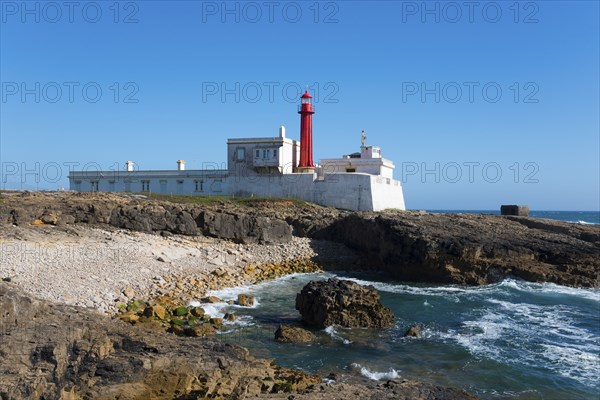 Old lighthouse on a rocky coast under a clear blue sky, Farol do Cabo Raso, São Brás de Sanxete