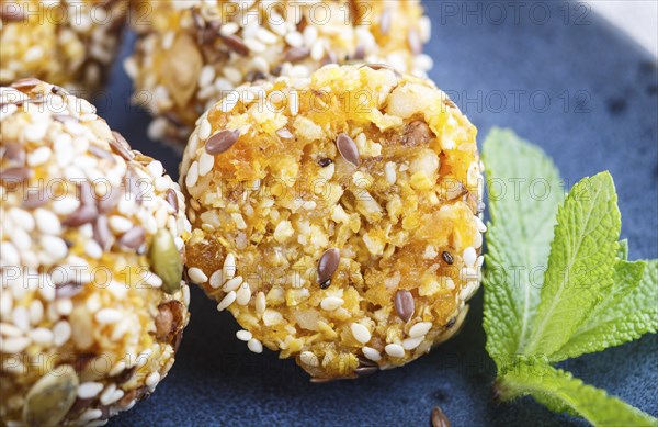 Energy ball cakes with dried apricots, sesame, linen, walnuts and dates with green mint leaves on a