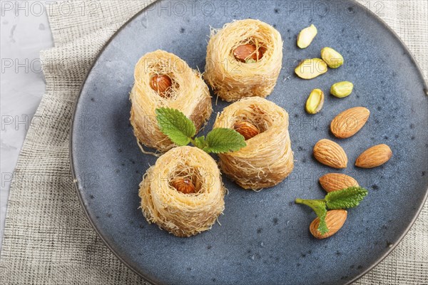 Kunafa, traditional arabic sweets in blue ceramic plate on a gray concrete background. side view,