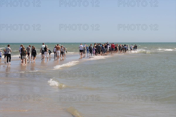Ttourists standing at the northern tip of Denmark where the Baltic Sea and North Sea meet at Skagen