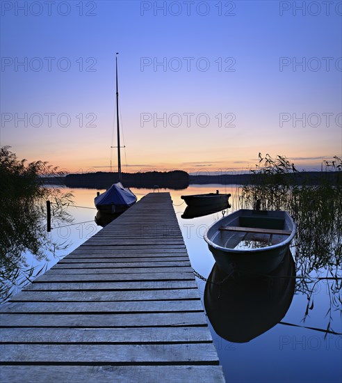 Quiet lake with jetty and boats after sunset at dusk, Großer Lychensee, Lychen, Brandenburg,
