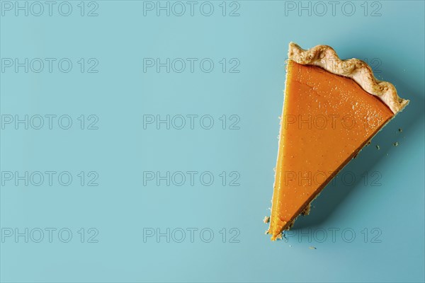 Top vie of single slice of pumpkin pie on blue background with copy space. Generative Ai, AI