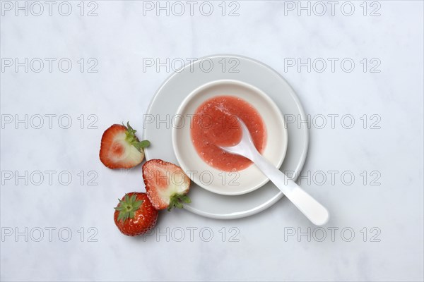 Strawberry sauce in small bowls and strawberries, strawberry coulis