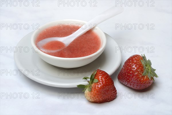 Strawberry sauce in small bowls and strawberries, strawberry coulis