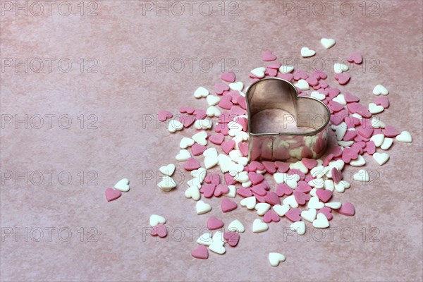 Heart-shaped cookie cutter and sugar hearts on a pink background