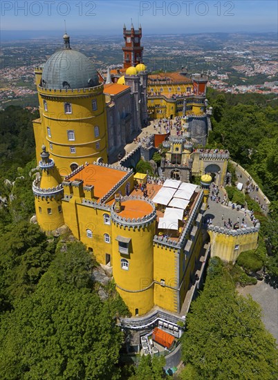 Historic castle in yellow on a hill with an impressive view and surrounded by forest, aerial view,