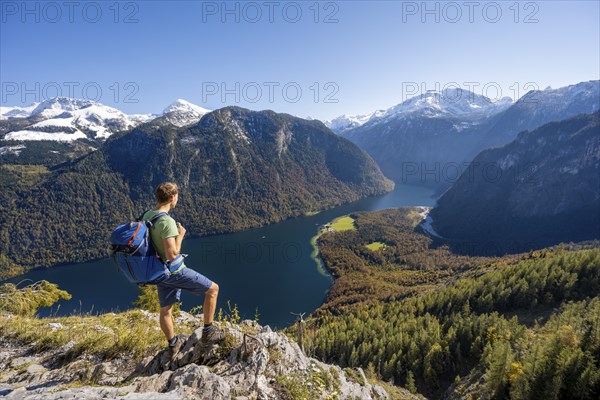 Mountaineer on an exposed mountain hiking trail, Rinnkendlsteig, view of the Königssee, autumnal