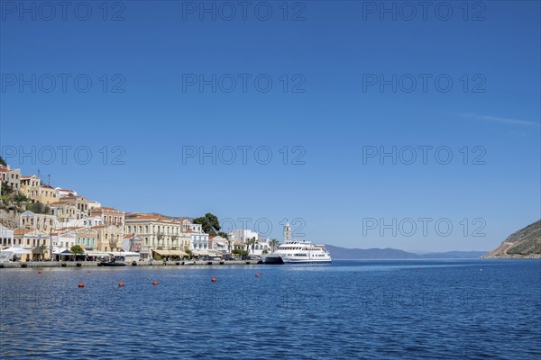 A picturesque coastal town with white houses and a boat in the clear blue sea under a bright blue