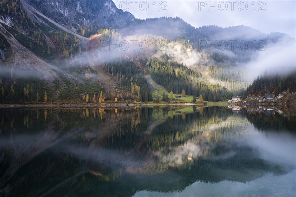 The Vordere Gosausee in autumn with a view of the Gasthof Gosausee. Sun and clouds. Overcast.