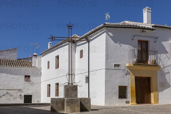 A quiet square with white houses and a central cross under a clear blue sky, Ronda, Andalusia,