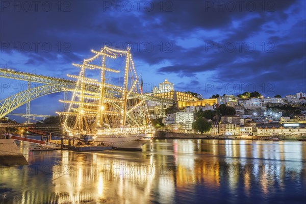 View of Vila Nova de Gaia city with a sailing ship and Dom Luis I bridge over Douro river in the