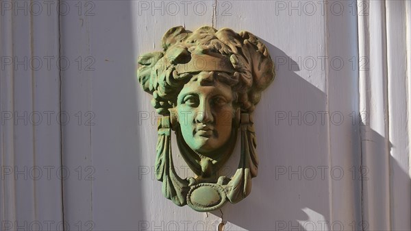 An antique bronze door knocker in the shape of a head, decorative and classically designed, Chora,