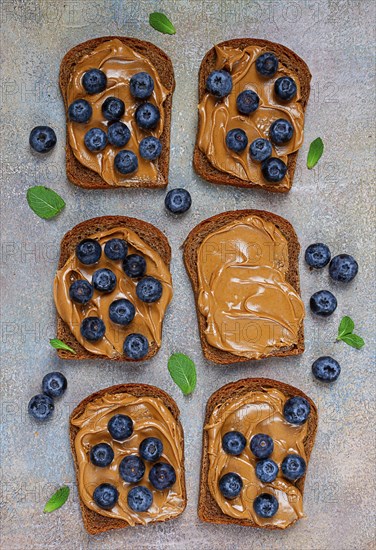 Rye bread with peanut paste and fresh blueberries, top view, no people