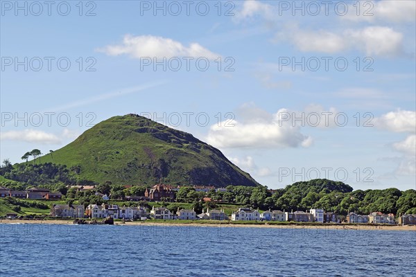 Coastal town with houses and a green hill in the background by the sea, North Berwick, Scotland,