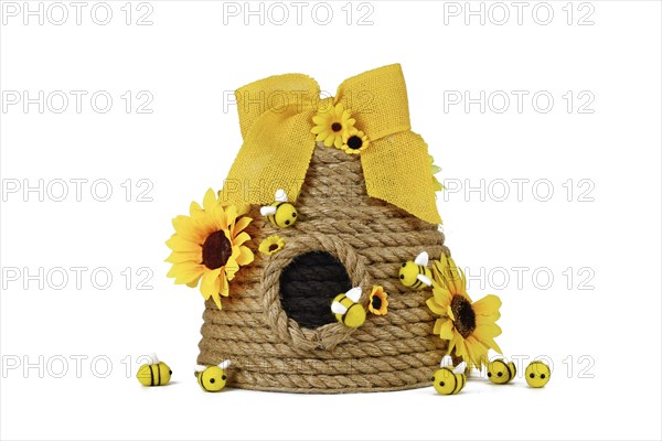 DIY rope beehive decoration with fake flowers, jute rope and cute felt bees on white background
