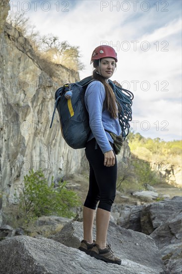 Portrait of female climber looking at camera at foot of rocky mountain. Extreme outdoor sport