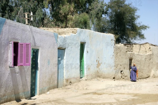 Bedouin woman in street with traditional houses in the Farafra Oasis in the Western Desert, Egypt,