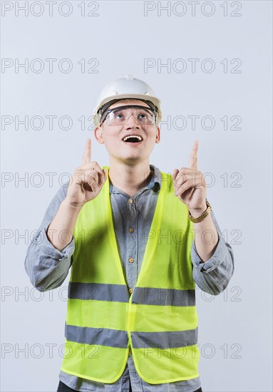 Surprised young architect pointing up. Amazed engineer pointing at an advertisement. Engineer with