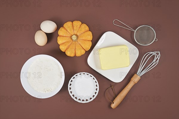 Pumpkin pie ingredients and baking tools on brown background